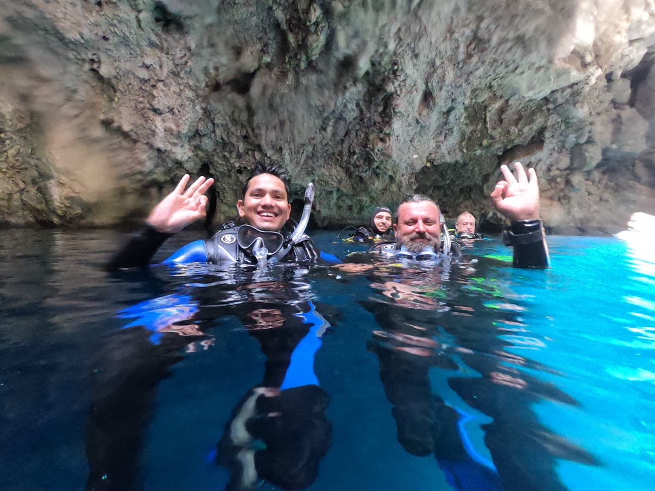 Surfacing inside a sea cave with fellow divers